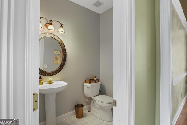 bathroom with toilet, a sink, visible vents, baseboards, and tile patterned floors