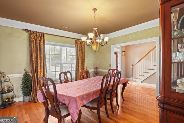 dining room with light wood-style flooring, a notable chandelier, visible vents, stairway, and crown molding