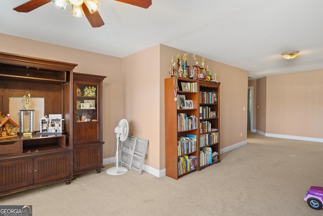 living area with ceiling fan, baseboards, and carpet flooring