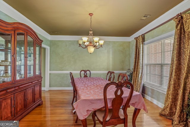 dining room featuring baseboards, light wood finished floors, visible vents, and a notable chandelier