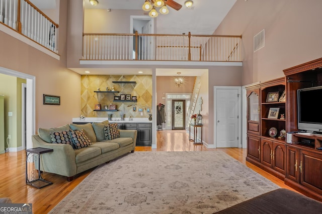 living room featuring light wood-type flooring, baseboards, and visible vents