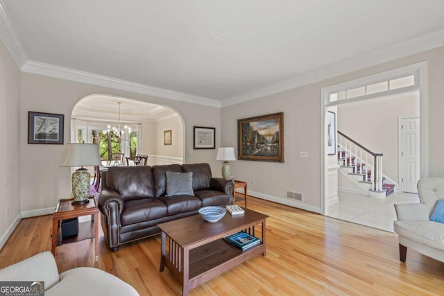 living area with light wood-style floors, visible vents, stairway, and arched walkways