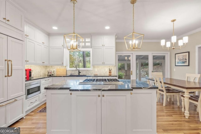 kitchen with an inviting chandelier, stainless steel gas stovetop, white cabinetry, and decorative backsplash