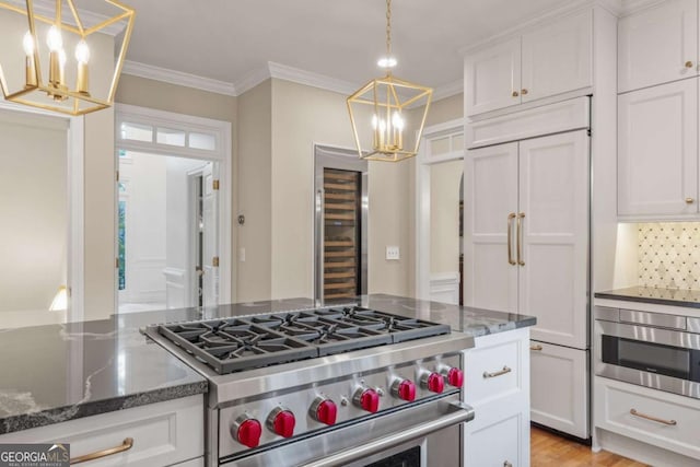 kitchen featuring high quality appliances, white cabinetry, dark stone counters, and crown molding