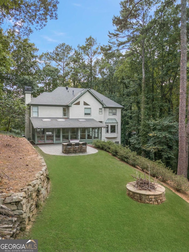 rear view of property with a patio, a yard, and a chimney