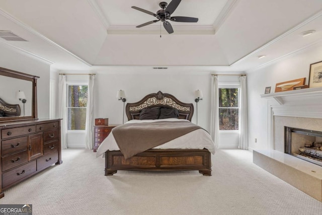 bedroom featuring ornamental molding, a tray ceiling, multiple windows, and light colored carpet