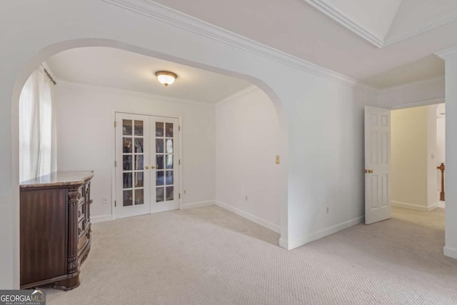 unfurnished room with arched walkways, french doors, light carpet, and crown molding