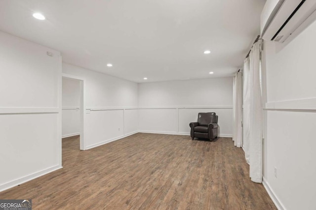 below grade area with baseboards, a wall mounted AC, wood finished floors, and recessed lighting