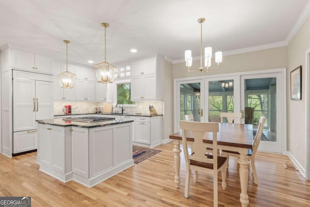 kitchen with a chandelier, paneled fridge, a sink, and white cabinets