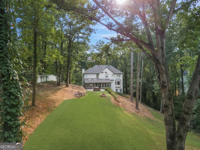 view of front of home featuring fence, a fire pit, and a front lawn