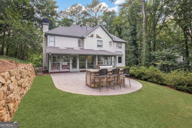 rear view of property featuring a chimney, outdoor dry bar, a lawn, a sunroom, and a patio area