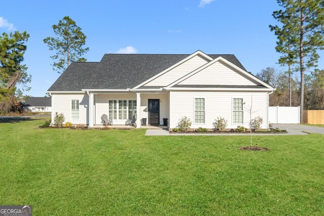 view of front of home featuring roof with shingles, a front yard, and fence