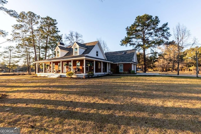 view of front of home with covered porch, a chimney, and a front yard