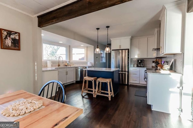 kitchen featuring a sink, a kitchen island, a kitchen breakfast bar, appliances with stainless steel finishes, and backsplash