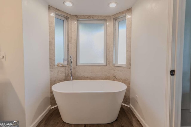 full bath with a freestanding tub, baseboards, and wood finished floors