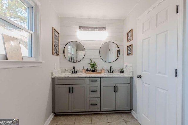 full bath featuring baseboards, double vanity, a sink, and tile patterned floors