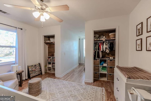 bedroom with light wood-style flooring, visible vents, baseboards, a ceiling fan, and a closet