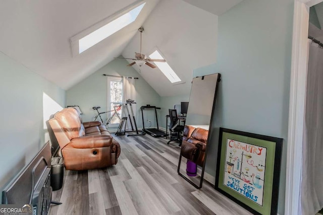 interior space with vaulted ceiling with skylight, wood finished floors, and a ceiling fan