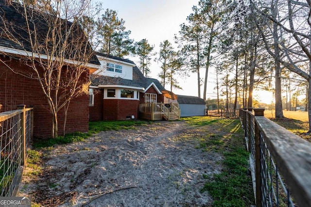 back of property featuring fence, an outdoor structure, and brick siding