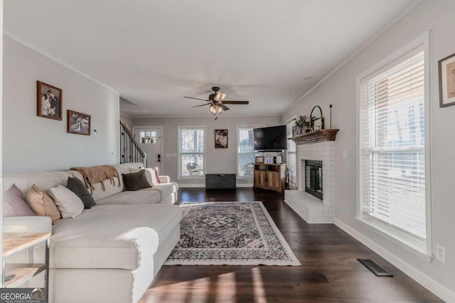 living area with a wealth of natural light, ornamental molding, dark wood-type flooring, and visible vents