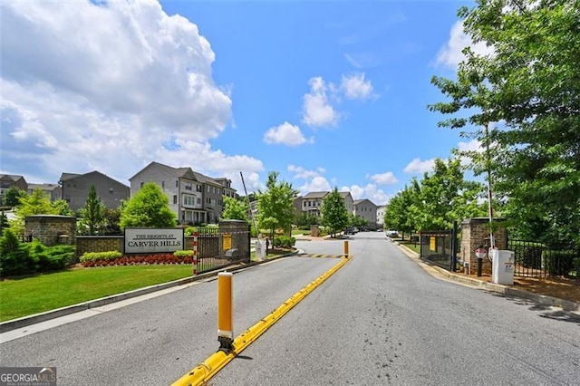 view of street featuring curbs, a gated entry, and a residential view