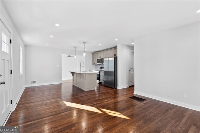 kitchen featuring light countertops, appliances with stainless steel finishes, visible vents, and a kitchen breakfast bar