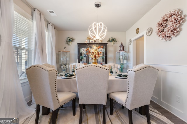 dining area featuring wood finished floors, visible vents, and a chandelier