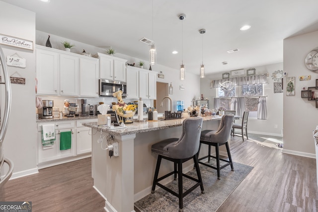 kitchen featuring visible vents, stainless steel microwave, dark wood-style floors, white cabinetry, and freestanding refrigerator