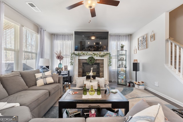 living area featuring visible vents, baseboards, a ceiling fan, and a premium fireplace