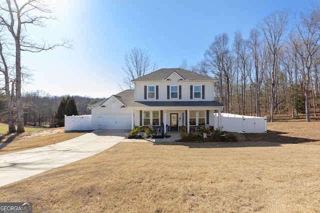 traditional home with a porch, concrete driveway, fence, and an attached garage