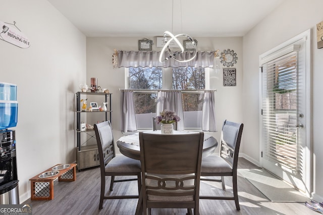 dining space with baseboards, plenty of natural light, a notable chandelier, and wood finished floors