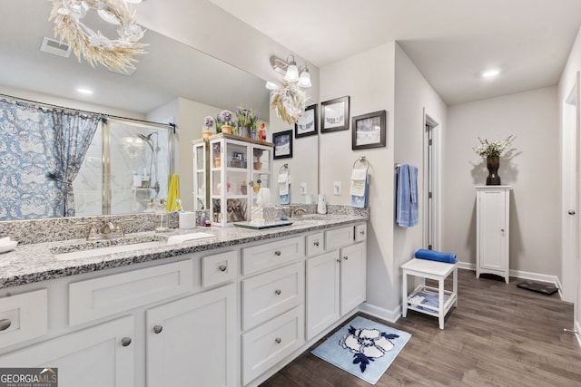 bathroom with visible vents, a sink, curtained shower, wood finished floors, and double vanity