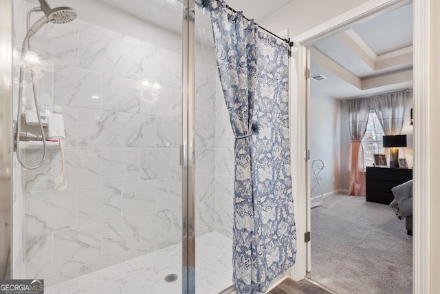 ensuite bathroom with ensuite bathroom, a raised ceiling, a stall shower, and crown molding
