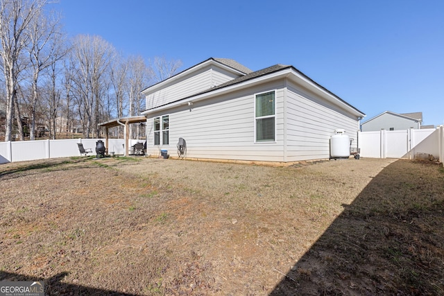 rear view of property with a gate, a fenced backyard, and a lawn