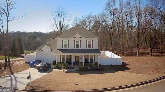 traditional-style home with covered porch, stucco siding, concrete driveway, and fence