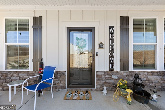 view of exterior entry featuring board and batten siding and stone siding