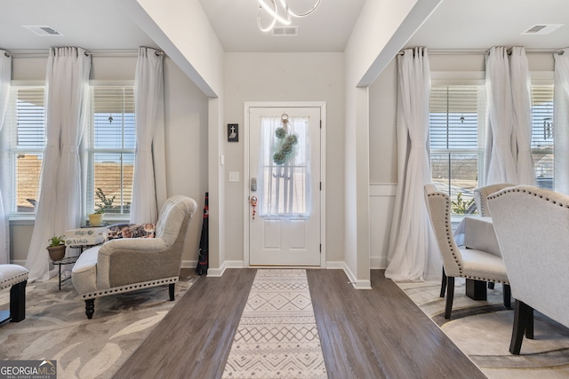 entrance foyer with a wealth of natural light, a notable chandelier, and wood finished floors