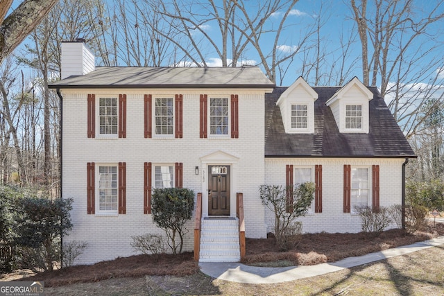 colonial house with a chimney and brick siding