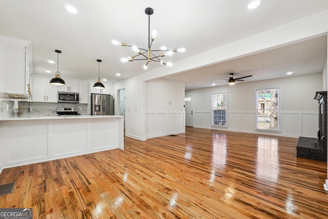 kitchen with tasteful backsplash, open floor plan, a peninsula, stainless steel appliances, and light countertops