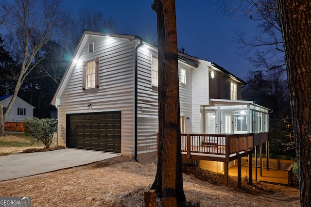 property exterior at twilight featuring a garage, driveway, and a wooden deck