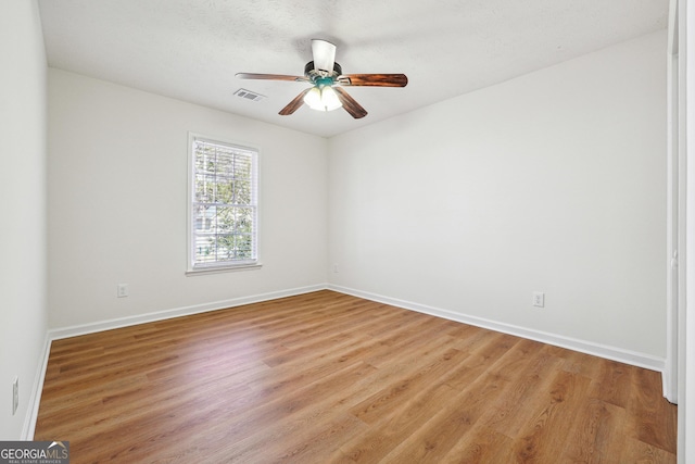 unfurnished room featuring baseboards, light wood finished floors, visible vents, and a ceiling fan