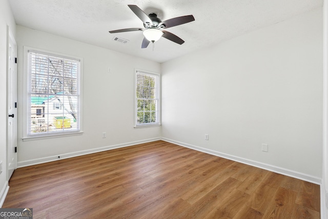 spare room featuring a ceiling fan, a textured ceiling, baseboards, and wood finished floors