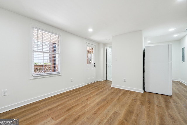 unfurnished room featuring light wood-style flooring, electric panel, baseboards, and recessed lighting