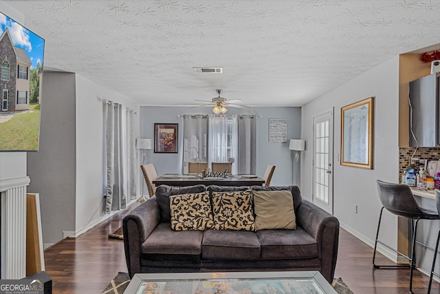 living room with a textured ceiling, ceiling fan, wood finished floors, and visible vents