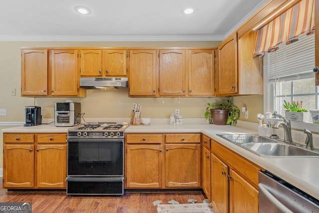 kitchen featuring range with gas stovetop, wood finished floors, stainless steel dishwasher, under cabinet range hood, and a sink