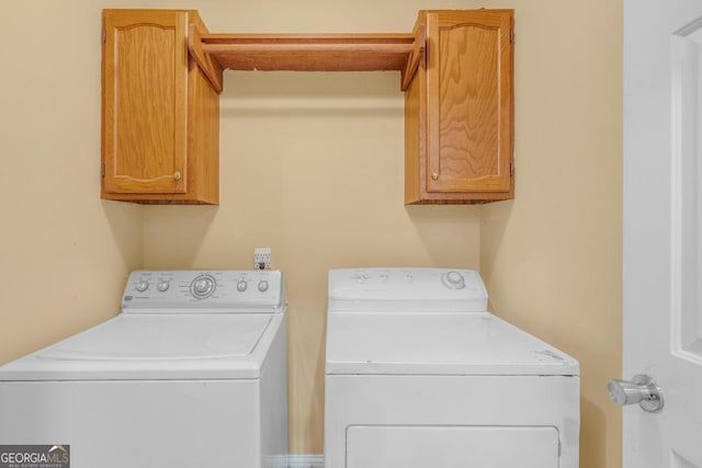 clothes washing area featuring cabinet space and washer and clothes dryer