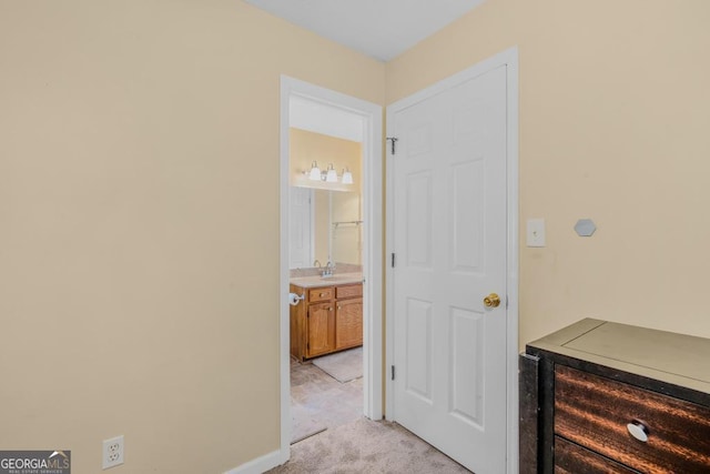 interior space featuring light carpet, a sink, and baseboards