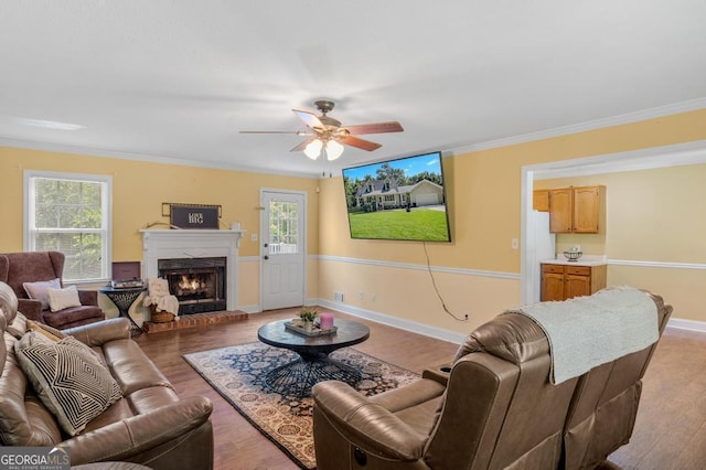 living area with a warm lit fireplace, plenty of natural light, and wood finished floors