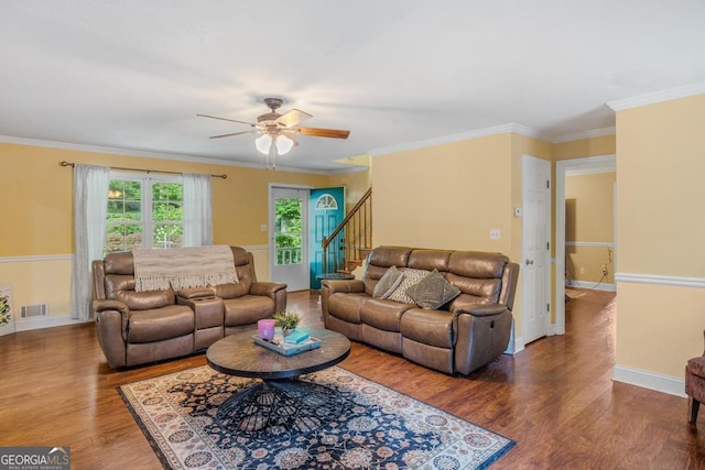 living room featuring baseboards, visible vents, ornamental molding, and wood finished floors