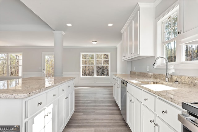 kitchen with a wainscoted wall, a sink, stainless steel dishwasher, ornamental molding, and ornate columns